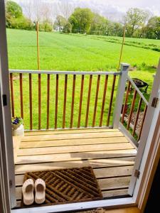 a wooden porch with two pairs of shoes on it at Whiskers and Woods Shepherd Hut 