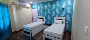 two beds in a room with a blue wall at Mohit Paying Guest house in Varanasi