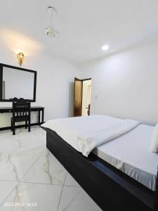 a white bedroom with a bed and a desk at Ayaa Luxury Apartment 3rd Floor Zanzibar in Ngambo