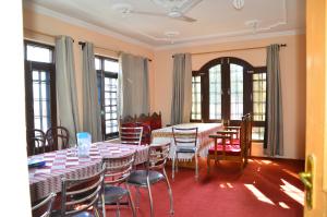 ein Esszimmer mit Tischen, Stühlen und Fenstern in der Unterkunft Hotel John's Palace in Srinagar