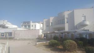 duży biały budynek z krzakami przed nim w obiekcie HOTEL PARADISE w mieście Porto Cesareo