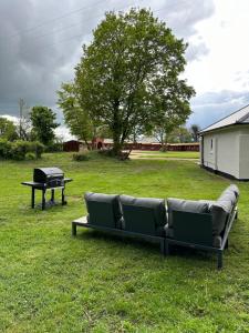 a couch sitting in the grass next to a grill at The Jockey's Lodge @ Danebury in Stockbridge