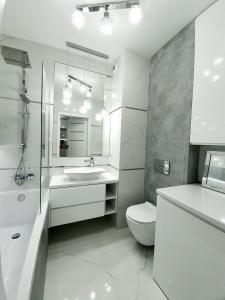 uma casa de banho branca com um lavatório e um WC em Apartament w Centrum em Grodzisk Mazowiecki