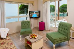 a living room with two chairs and a tv at Herods Palace Hotels & Spa Eilat a Premium collection by Fattal Hotels in Eilat