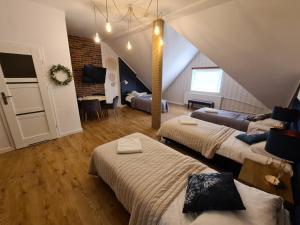 a attic room with two beds and a living room at Hotel Kurpia Arte in Nowogród