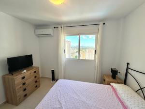 een slaapkamer met een bed, een televisie en een raam bij Apartamento a pie de Playa NTRLL in La Venteta