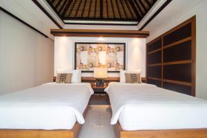 une chambre avec deux lits et un tableau au mur dans l'établissement Rekso Villa, à Jimbaran 34 autres photos