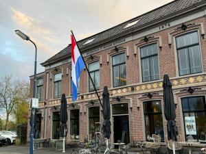 un edificio con una bandera y sombrillas delante de él en Elfstedenstate en Easterein