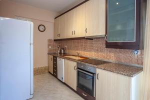 a kitchen with wooden cabinets and a sink and a refrigerator at Betty seaside villa in Pefkochori +41 photos
