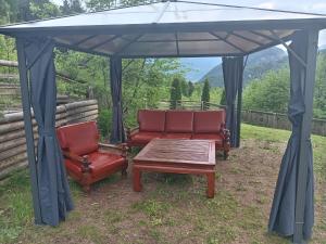Duas cadeiras e uma mesa debaixo de um gazebo em Chalet cima 12 Valle di Sella em Borgo