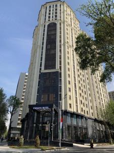 un grand bâtiment blanc dans une rue de la ville dans l'établissement Hotel Panorama, à Douchanbé