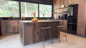 a kitchen with a counter with stools and a refrigerator at Overstory Forest Cabins Ironwood in Cape Town +5 photos