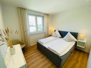 um pequeno quarto com uma cama e uma janela em Seeliebe Apartments Schwerin - am See, Seeblick, PKW, Sauna, XXL-Balkon, Terrasse, modern em Schwerin