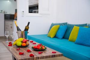 a table with fruit and wine glasses and a blue couch at Vivid Caves 1 bedroom Cavehouse in Foinikiá
