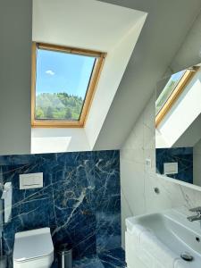 a bathroom with a sink and a toilet and a window at Penzion Mlyn - Bystra in Brezno