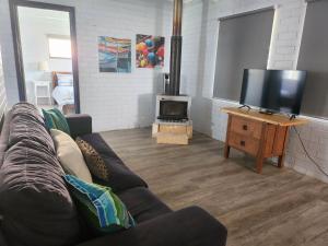 sala de estar con sofá y TV de pantalla plana en Sands Beach House, en Jurien Bay