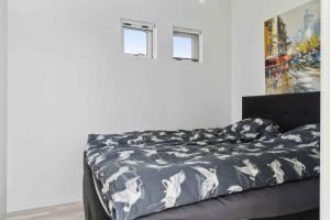 a bed with a black and white comforter and two windows at Modern Summer House With Fantastic Skylight, in Slagelse