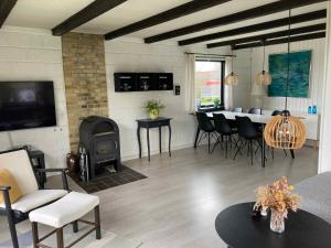 - un salon avec une cheminée, une table et des chaises dans l'établissement Cozy Cottage Close To The Beach, à Bogense