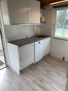 a small kitchen with white cabinets and a sink at Summer House With Shelter And Water View, in Løgstør