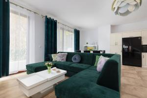 a living room with a green couch and a table at Spacious Apartment in Wisełka with Parking and Seasonal Swimming Pool by Renters Prestige in Wisełka