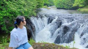 een vrouw op een rots voor een waterval bij Hatago Nagomi in Nikko