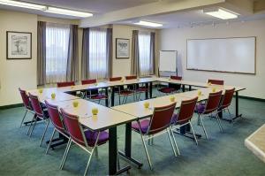 uma sala de aula com mesas e cadeiras e um quadro branco em Lakeview Inns & Suites - Okotoks em Okotoks