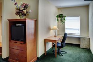 a hotel room with a desk and a television and a desk and chair at Lakeview Inns & Suites - Okotoks in Okotoks