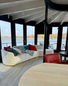 una sala de estar con 2 sofás blancos y sillas rojas en 360 Grad Floating Home Shanti 2, en Gallin