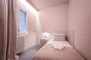 a small white bedroom with a bed and a window at Sweet Inn - Gaudi Avenue in Barcelona