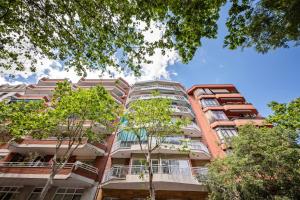 バルセロナにあるSweet Inn - Gaudi Avenueの手前に木々が植えられたアパートメントビル