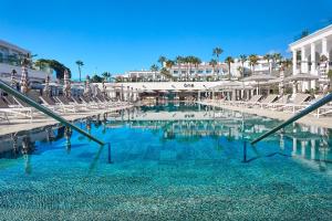a large swimming pool with chairs and blue water at Princess Inspire Tenerife - Adults Only in Adeje