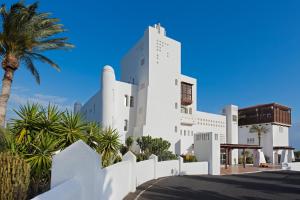a white building with a palm tree at Club Jandía Princess in Playa Jandia