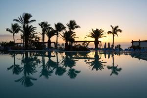 une piscine avec des palmiers et le coucher de soleil en arrière-plan dans l'établissement Club Jandía Princess, à Playa Jandía 32 autres photos