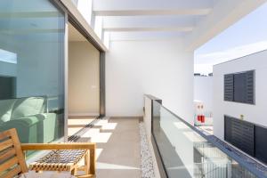 d'un balcon avec des murs en verre et un banc en bois. dans l'établissement Maruxía Beach and Pool apartemnt, à Abades