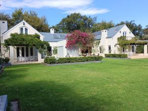 a large white house with a green yard at Alzare Villa in Greyton