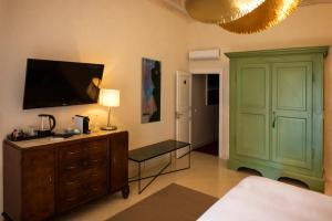 una camera da letto con armadio verde e TV a parete di Aria Rooms and Terrace a Noto
