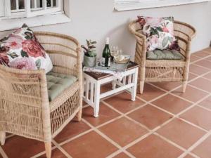 dos sillas de mimbre y una mesa con una botella de vino en Wylde Rose Cottage en Pietermaritzburg