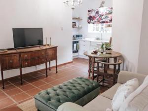 sala de estar con TV y mesa en Wylde Rose Cottage, en Pietermaritzburg