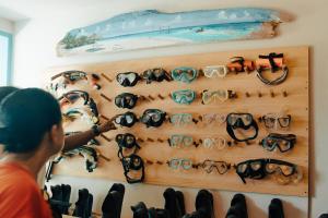 un homme qui regarde une exposition de lunettes de soleil sur un mur dans l'établissement Ocean Pearl Maldives at Gulhi Island, à Gulhi