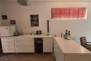 La cuisine est équipée d'un comptoir blanc et d'un réfrigérateur. dans l'établissement Garden flat for working person, à Pierre van Ryneveld