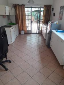 una cucina con armadietti bianchi e pavimento piastrellato di Garden flat for working person a Pierre van Ryneveld