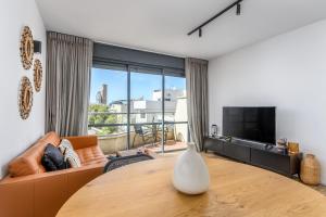 ein Wohnzimmer mit einem Tisch und einem Sofa in der Unterkunft Modern & Sunny 1 BDR w balcony and parking in Tel Aviv
