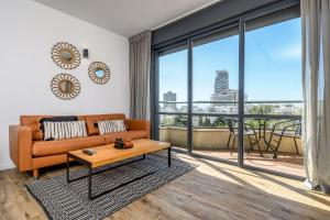 ein Wohnzimmer mit einem Sofa und einem großen Fenster in der Unterkunft Modern & Sunny 1 BDR w balcony and parking in Tel Aviv
