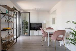 a dining room with a white table and pink chairs at Time suits with beautiful view and pool in Valencia