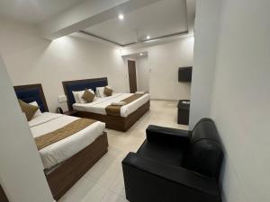 una habitación de hotel con 2 camas y una silla en JN Guestline en Devanahalli-Bangalore