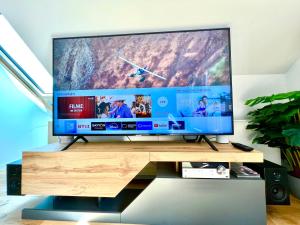 een grote flatscreen-tv zittend op een houten standaard bij Traum Berg - Koppelberg in Traben-Trarbach