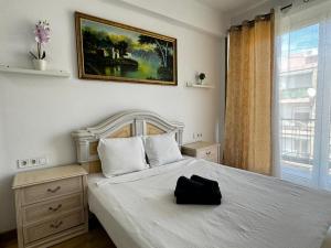 Un dormitorio con una cama blanca con una bolsa negra. en Grandera Apart`s - Assutzena 5, en Valencia