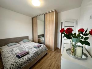 a bedroom with a bed and a vase of red roses at Tower Apartments Centrum in Spišská Nová Ves