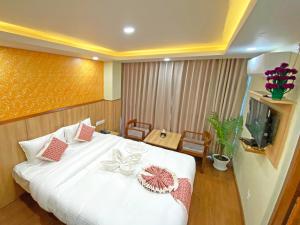 um quarto com uma cama branca e uma televisão em Hotel Lumbini Airport em Catmandu