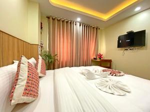 1 dormitorio con 1 cama blanca y TV en la pared en Hotel Lumbini Airport en Katmandú